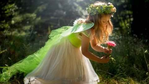 A young girl dressed as a fairy in a garden.