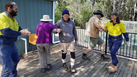 Five people dancing on an outdoor deck.