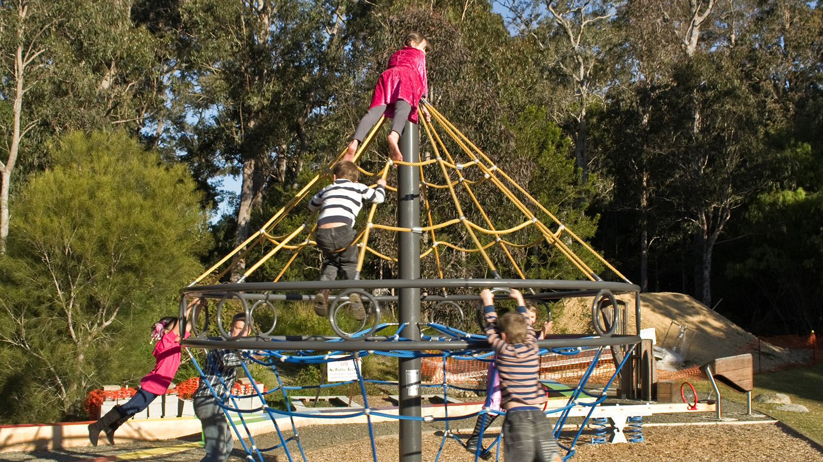 Image Children playing on oversized rope merry-go-round play equipment