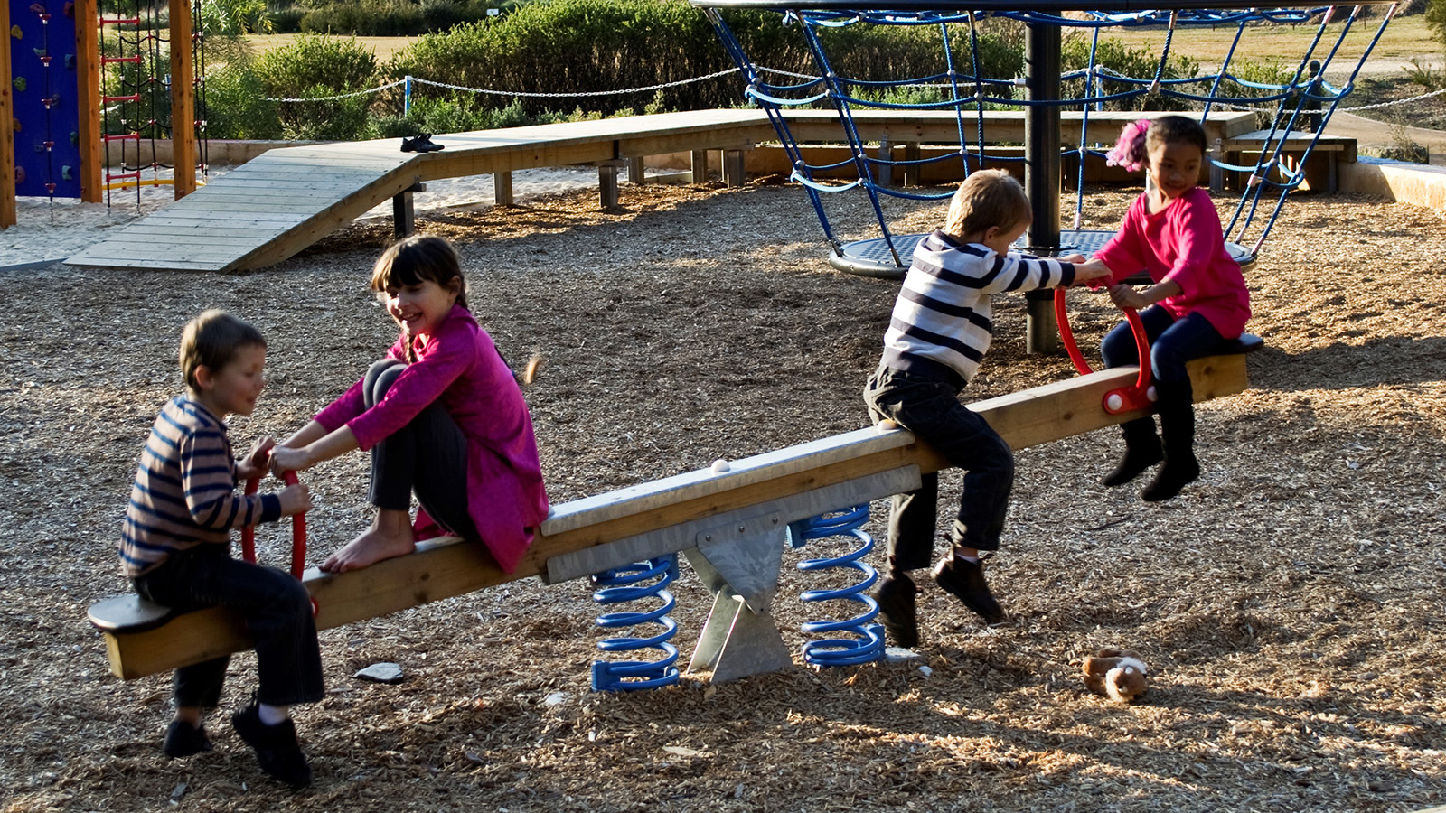 Image four children using seesaw play equipment