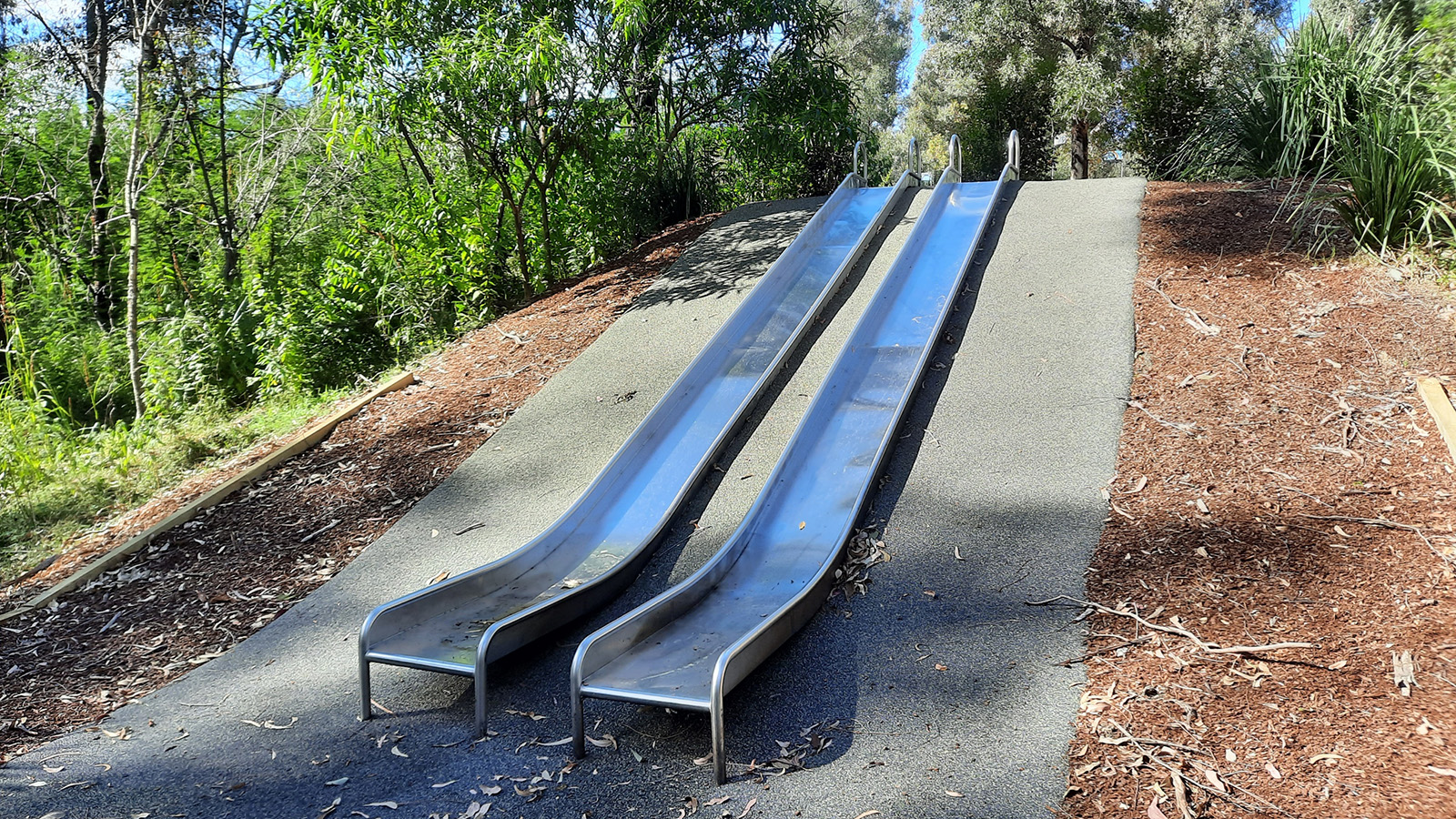 Image Two outdoor slides on a hillside