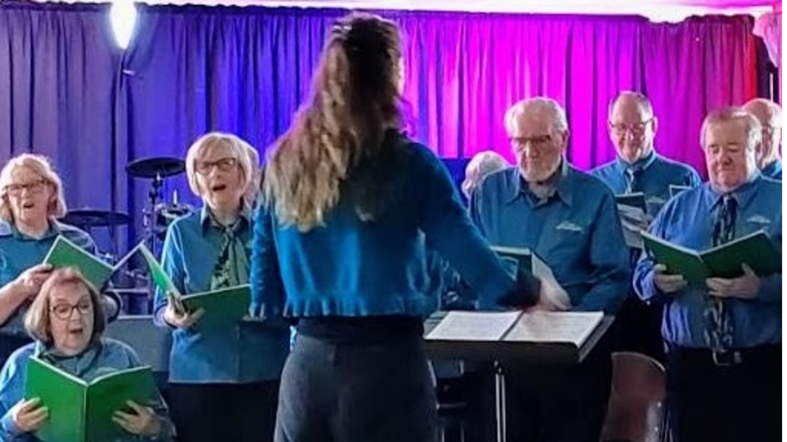 A woman conducting a choir group. banner image